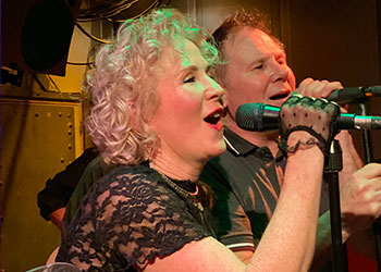 Close up of two band members singing on stage
